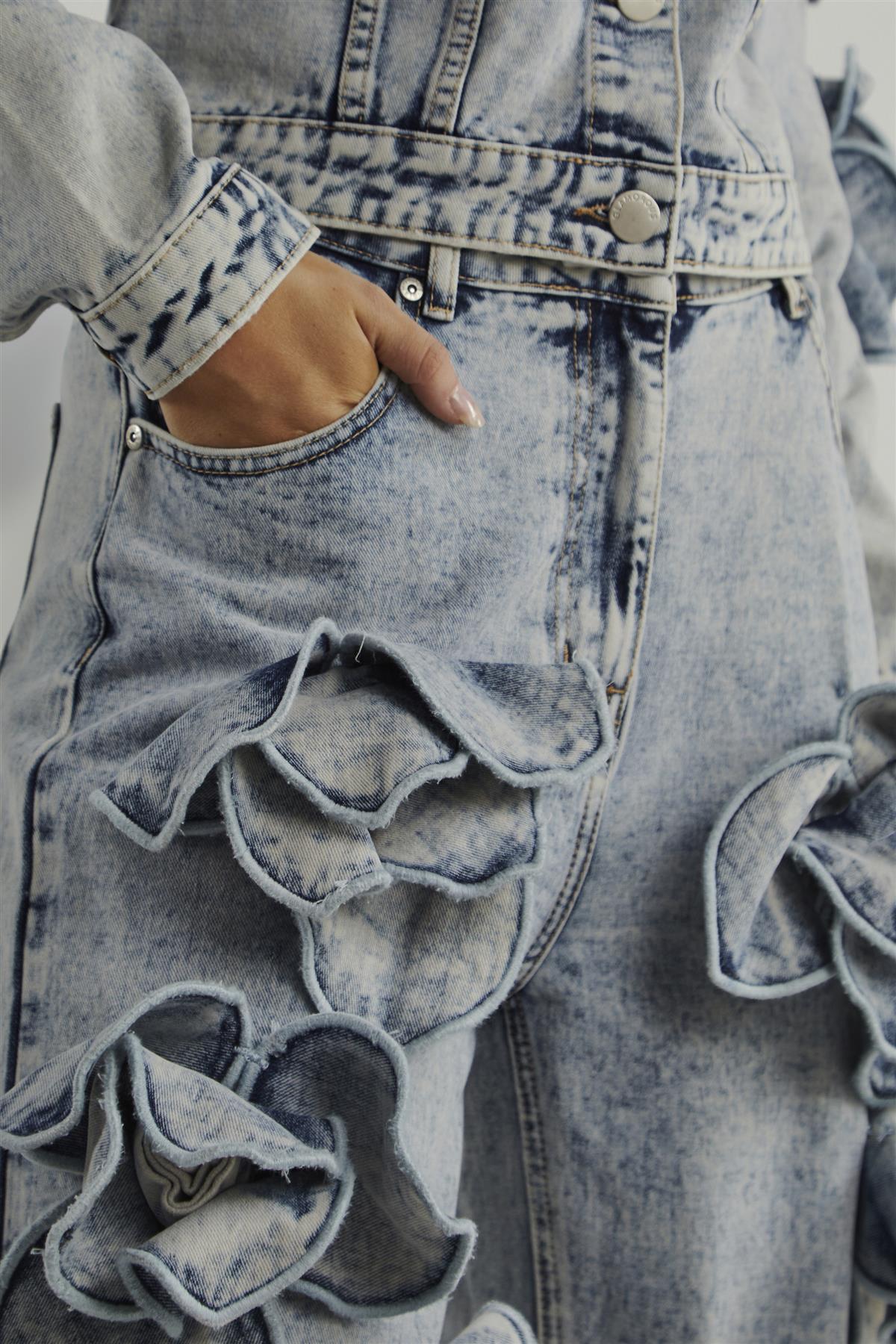 Close-up of a person wearing distressed denim jeans with ruffled details.