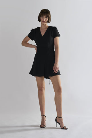 black V-neck mini-dress with short sleeves and a tie waist, paired with high heels By Glamorous