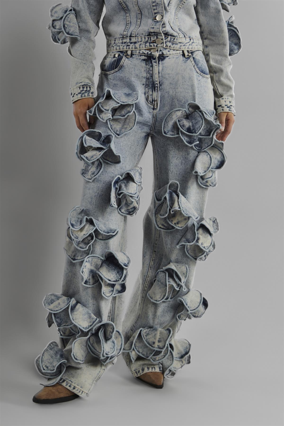 Denim pants with floral embellishments on a gray background
